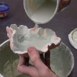 child glazing a clay bowl