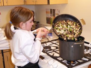 Child dumping food mixture into a pot