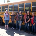 Teens standing outside of school bus