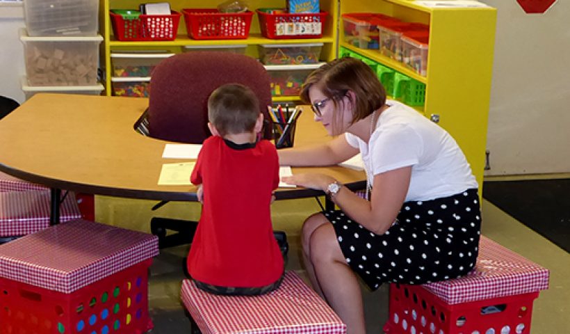 kindergarten teacher works with student
