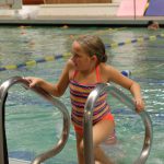 girl climbing ladder out of pool