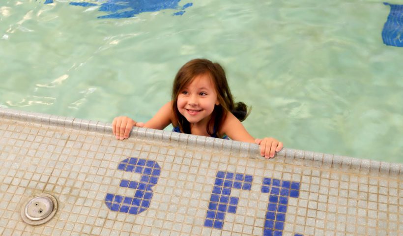 girl smiling at camera near 3 foot pool sign