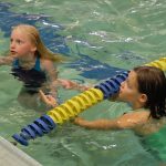 two girls in pool near lane divider